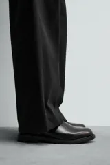 Bota estilo Chelsea de piel negra con elásticos laterales y suela con ligero tacón.