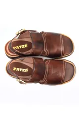 Sandalia de cuero marrón oscuro, estilo pescador cerrado en la punta y abierto en el talón con tira ajustable y hebilla dorada. Presenta costuras blancas visibles y suela de goma gruesa con plataforma y taco bajo.