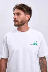 Remera blanca de manga corta con un pequeño estampado verde en el pecho que simula una caja abierta con un objeto dentro.