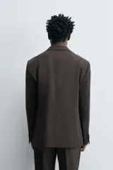 Blazer de corte regular confeccionada en tejido de lana. Presenta cuello con solapas de muesca, cierre frontal de un botón y manga larga con puños abotonados. Cuenta con bolsillos de vivo en el pecho, bolsillos con solapa en la cadera y aberturas en la parte posterior.