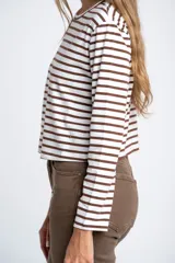 Remera de manga larga ajustada al cuerpo, con cuello redondo. Presenta un patrón de rayas horizontales anchas en color blanco y marrón oscuro.
