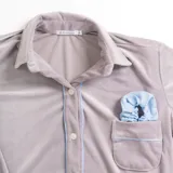 Pijama de dos piezas color rosa pálido, confeccionado en terciopelo. La camisa es de manga larga con botones frontales y bolsillo en el pecho. El pantalón es de corte recto con cintura elástica.