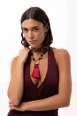 Collar corto con cadena de piedras naturales en tonos tierra y un dije central metálico en forma de herradura del que cuelgan tres borlas de seda en color bordó.