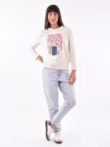 Remera de manga larga color blanco, con cuello redondo y estampa frontal en tono rosado que incluye un diseño de marco con moño y la frase "live simply love sincerely".