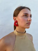 Aros tipo caravanas con diseño de flor irregular en color rojo vibrante y centro con detalle de pequeñas perlas.