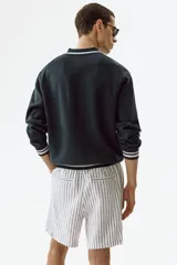 Short de lino y viscosa, color blanco con rayas verticales delgadas, corte relajado, cintura elástica con cordón de ajuste y bolsillos laterales.