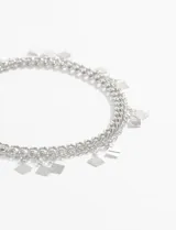 Tobillera plateada de doble cadena con dijes colgantes en forma de rombo.