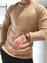 Buzo de punto trenzado color camel, con cuello redondo y mangas largas. Diseño texturizado con patrón de trenzas en relieve.