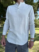 Camisola de lino color beige de manga larga, con cuello mao y cierre frontal parcial de tres botones.