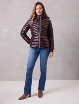 Campera puffer de acabado satinado en color marrón oscuro. Presenta un diseño capitoneado con líneas en V, cierre frontal metálico, capucha fija y puños internos de tejido elastizado con abertura para el pulgar. Incluye bolsillos laterales con cierre invisible y logo metálico en la manga.