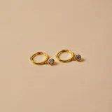 Aros tipo argolla pequeña en plata 925 con baño de oro, con un dije colgante circular engastado con una circonia brillante.