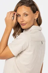 Camisa de lino de manga corta con cuello camisero, cierre frontal de medio botón con botones metálicos personalizados y dos bolsillos en el pecho.