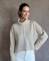 Sweater color crema de tejido de punto con cuello alto y corte holgado.