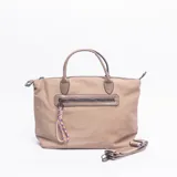 Cartera tipo bolso de mano color beige, confeccionada en material sintético liso. Cuenta con doble asa superior, cierre principal con cremallera, un bolsillo frontal con cierre y un detalle decorativo de cordón trenzado multicolor. Incluye una correa larga ajustable y extraíble.