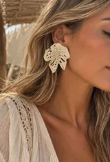 Aros grandes con diseño de flor en color beige claro, con detalles calados y centro texturizado.