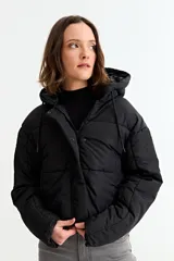 Campera puffer corta de color negro, con capucha, cierre frontal con cremallera y solapa con botones a presión.