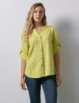 Blusa color verde claro de lino marca Cupio, con cuello a la base, escote en V y abertura con botones. Tiene un bolsillo en la parte delantera y mangas 3/4 regulables con presilla y botón.