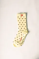 Medias largas color amarillo claro con estampado de lunares marrones. Tienen un corazón rojo con la letra 'R' bordada en la parte superior y la palabra 'ROTUNDA' en el lateral.