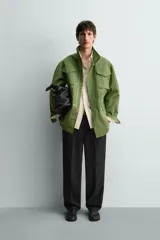 Parka estilo militar color verde, de corte relaxed fit, cuello subido y manga larga. Cuenta con bolsillos de plastrón con solapa en el pecho y en la cadera, cintura ajustable con cordón interior y cierre frontal con cremallera oculta por solapa con botones a presión.