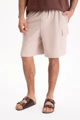 Bermuda cargo de felpa sin friza, color beige, con cintura elástica y bolsillos laterales con solapa.