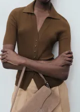 Jersey de punto fino color marrón, con cuello camisero, cierre frontal con botones y diseño entallado de manga corta.