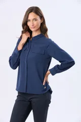 Blusa tipo camisa de manga larga en color azul marino, confeccionada en tela suave y sedosa con doble capa en el frente. Presenta cuello clásico, cierre frontal con botones ocultos y un bolsillo en el pecho.