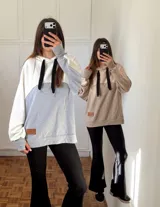 Canguro con capucha y cordones negros, diseño bicolor con mangas largas y puños con abertura para el pulgar. Presenta un parche de cuero sintético en la parte inferior frontal.