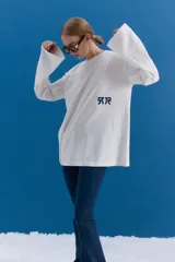 Remerón de manga larga y corte holgado, color blanco, con estampa serigráfica en la espalda que incluye motivos orientales como una rama de flores, un pez koi, una mariposa y texto en japonés. Presenta un parche decorativo en la parte inferior.