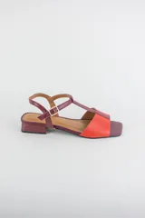 Sandalias de cuero combinadas en negro y marfil, con diseño de tiras en T, taco cuadrado bajo y pulsera con hebilla ajustable al tobillo.