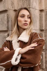 Tapado estilo gamulán con interior de corderito sintético, cuello amplio, bolsillos delanteros y cierre frontal con alamares. Diseño de corte oversized con terminaciones a contratono.