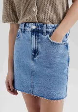 Minifalda de jean azul con bolsillos delanteros y traseros, corte recto y ruedo desflecado.