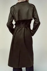 Abrigo largo color marrón oscuro con efecto ante, cuello solapa, manga larga con trabillas en los hombros y bolsillos delanteros de vivo. Presenta un bajo con abertura en la espalda y cierre frontal cruzado con botones, complementado con un cinturón a tono.