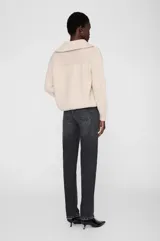 Sweater de tejido acanalado con cuello alto y cierre frontal parcial. Presenta un diseño de corte holgado con mangas largas y puños ajustados.