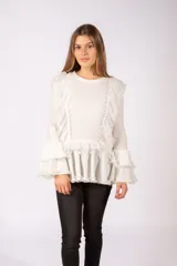 Sweater de punto acanalado color blanco, con diseño de volados en el frente y en las mangas acampanadas. Presenta detalles de encaje y terminaciones desflecadas.