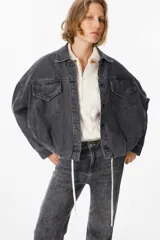 Chaqueta de jean color gris lavado, con corte oversize, mangas amplias y bolsillos frontales con solapa. Presenta cierre frontal con botones metálicos y cuello clásico.