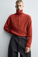 Jersey de punto de corte relajado, color marrón, con cuello perkins y cierre frontal de cremallera. Presenta manga larga y acabados en rib en puños y bajo.