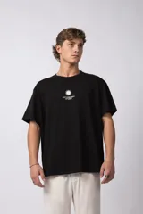 Remera negra de corte oversize, confeccionada en algodón premium. Presenta un diseño minimalista con un pequeño logo estampado en el pecho que incluye un sol y el texto VCP CONCEPT STUDIO.