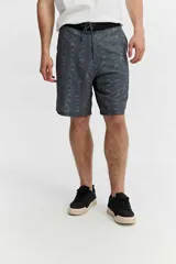 Short de baño estilo surf color gris, de largo medio, con estampado geométrico abstracto y cordón ajustable en la cintura. Incluye bolsillo trasero con solapa.