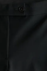 Pantalón tobillero negro de corte bootcut, con raya marcada adelante y atrás. Cuenta con cintura estándar con elástico oculto, cierre con pretina prolongada y botones, bolsillos al bies y bolsillo trasero ribeteado.