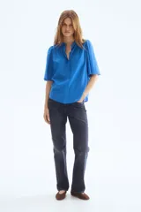 Blusa oversized azul de mezcla de algodón y viscosa, con cuello mao, botonadura frontal y mangas cortas abullonadas con terminación de broderie.