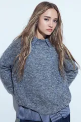 Sweater de tejido suave color marrón con diseño de líneas bordadas en color rojo. Presenta cuello redondo, manga larga y calce relajado.
