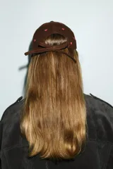 Gorra con visera de pana color marrón, con bordados de corazones rojos distribuidos por toda la superficie. Cuenta con cierre ajustable en la parte posterior.