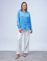 Camisa de satén estampado en blanco y negro, con cuello con solapa, escote en V y abertura central con botones.