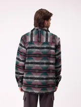 Camisa de manga larga con diseño de estampado étnico en tonos azules y beige. Presenta cuello clásico, cierre frontal con botones y bolsillos en el pecho.