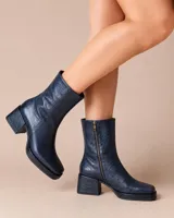 Botas de caña media en cuero azul oscuro con textura arrugada, diseño de punta cuadrada, taco cuadrado y cierre lateral.