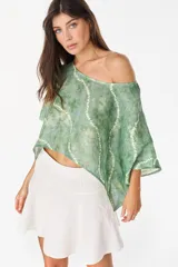 Blusa verde de lino con diseño batik, escote bote que deja un hombro al descubierto y mangas cortas amplias.