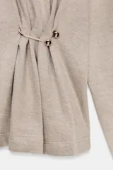 Top de cuello alto y manga larga, confeccionado en tejido de algodón gris melange. Presenta un diseño con frunces laterales ajustados mediante un aplique metálico decorativo.