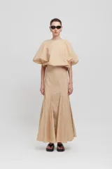 Falda larga color beige, de talle alto, con aberturas verticales y bajo acampanado.