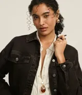 Campera trucker de jeans negro con efecto tintado, cuello clásico, cierre frontal con botones, solapas en el pecho con botones y corte holgado.