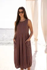 Vestido maxi sin mangas de corte fluido, con diseño a rayas verticales en tonos azul y marrón. Presenta cuello redondo y bolsillos frontales aplicados.